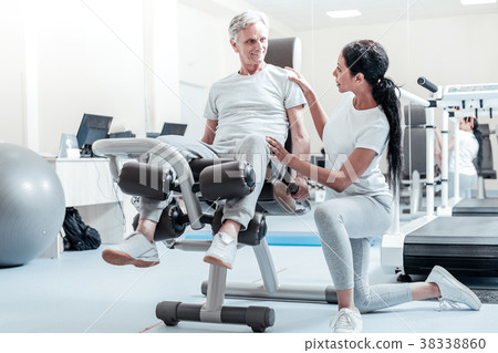 Alert old man on a training device and his trainer Alert old man on a training device and his trainer 38338860