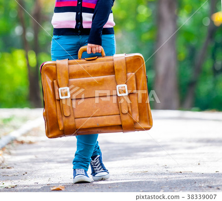 Young teen girt with suitcase in a park 38339007