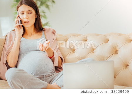 Serious occupied woman sitting and having phone 38339409