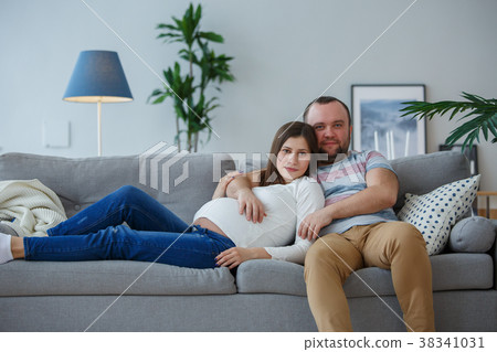 Photo of happy pregnant woman and man on gray sofa Photo of happy pregnant woman and man on gray sofa 38341031