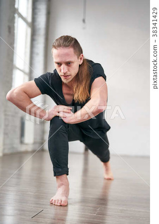 Young fit man stretching legs doing forward lunge. Young fit man stretching legs doing forward lunge. 38341429