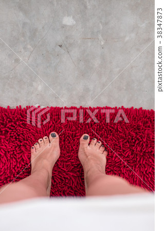 Woman feet on concrete floor with red carpet Woman feet on concrete floor with red carpet 38347873