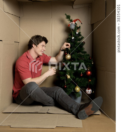 Guy is adorning christmas-tree inside little 38354101