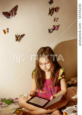 Little caucasian girl with a e-book in the bed Little caucasian girl with a e-book in the bed 38356288