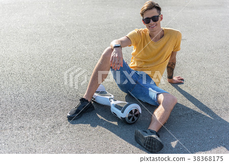 Outgoing boy situating near hoverboard Outgoing boy situating near hoverboard 38368175