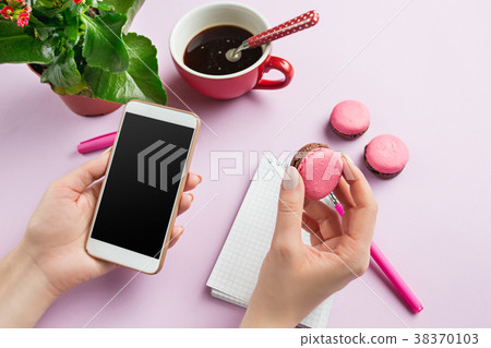 The female hands holding phone and french macarons The female hands holding phone and french macarons 38370103