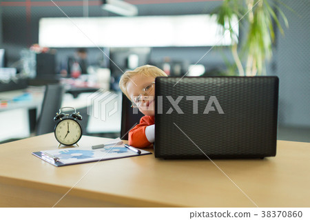 Cute boy sit at the desk in the office and uses 38370860