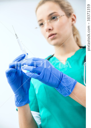Female vet prepares syringe to injection. Female vet prepares syringe to injection. 38371359