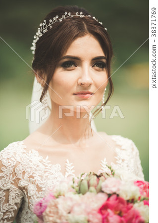 Beautiful bride in elegant white dress holding 38371769