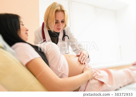 Doctor listen tummy of pregnant woman 38372933