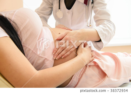 Doctor touch pregnant tummy with hands Doctor touch pregnant tummy with hands 38372934