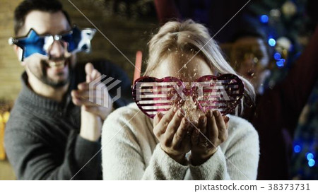 Young mother blowing gold glitter from her hands 38373731