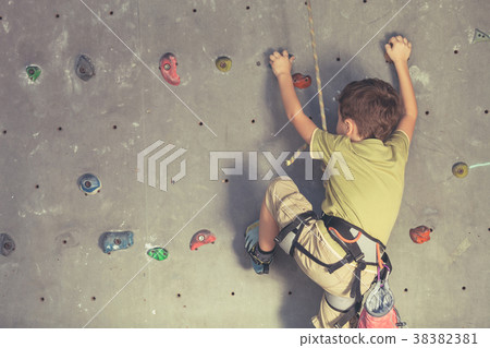 little boy climbing a rock wall indoor. 38382381