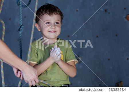 little boy and mother standing near a climbing  rock wall indoor 38382384