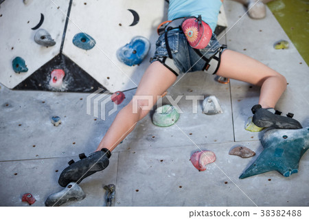 Teen girl climbing a rock wall indoor. Teen girl climbing a rock wall indoor. 38382488
