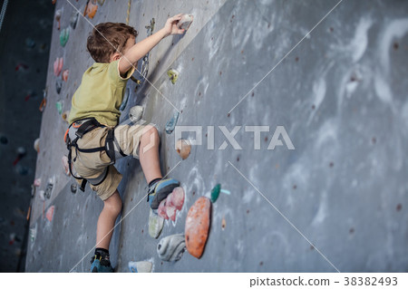 little boy climbing a rock wall indoor. 38382493