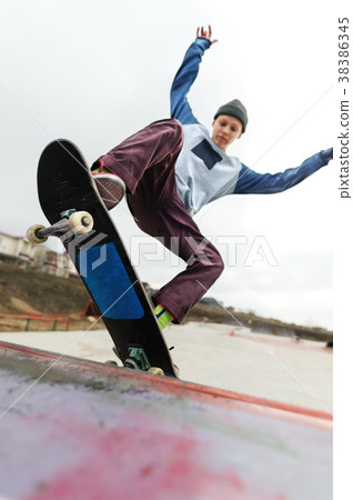 A teenager skateboarder in a hat does a Rocks 38386345