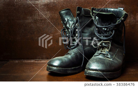 Old military boots against wooden background Old military boots against wooden background 38386476