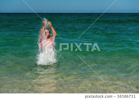 Girl bathing in to the sea and splashing water 38386731