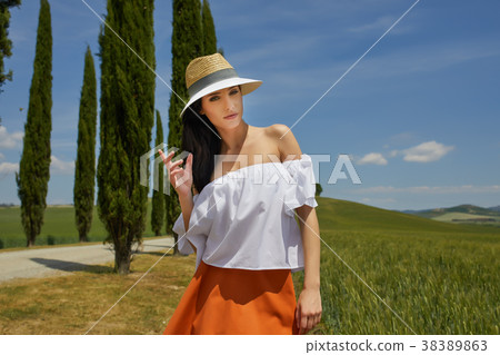Woman is walking along the road among the fields and a typical T Woman is walking along the road among the fields and a typical T 38389863