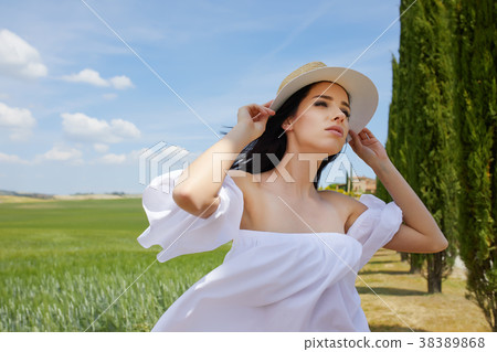 Woman is walking along the road among the fields and a typical T Woman is walking along the road among the fields and a typical T 38389868