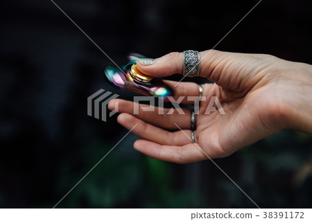 Girl's hand with fidget spinner. Holds a shiny 38391172