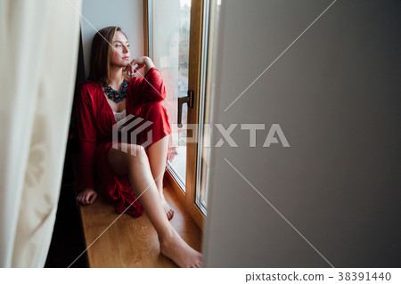 beautiful sexy girl in a red robe is sitting on 38391440