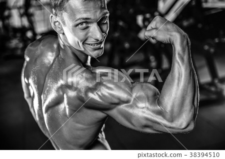 Handsome model young man training arms in gym Handsome model young man training arms in gym 38394510