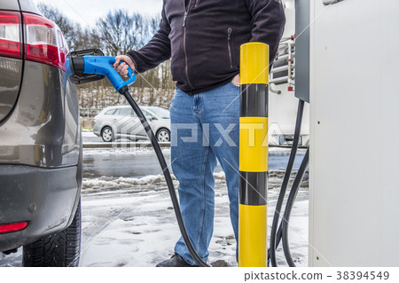 Man charging his electric car 38394549