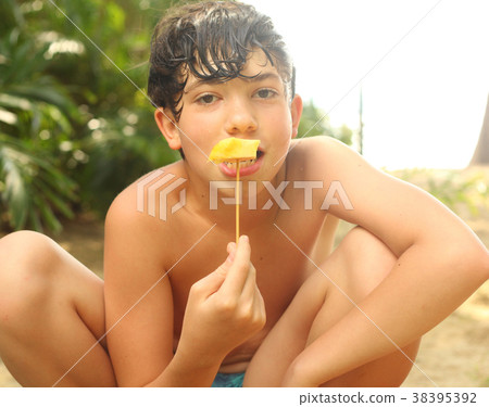 teenager boy eat pineapple piece on stick close up 38395392