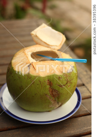 green coconut with choped off top and straw 38395396