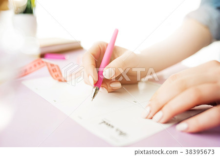 The female hands holding pen. The trendy pink desk The female hands holding pen. The trendy pink desk 38395673