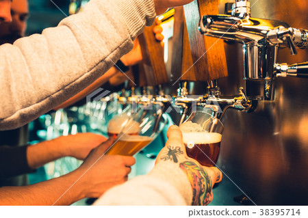 Hand of bartender pouring a large lager beer in 38395714