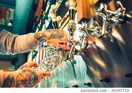 Hand of bartender pouring a large lager beer in Hand of bartender pouring a large lager beer in 38395719