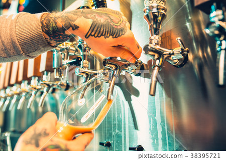 Hand of bartender pouring a large lager beer in Hand of bartender pouring a large lager beer in 38395721