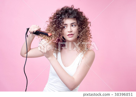 Beautiful young woman making curls with curling 38396851