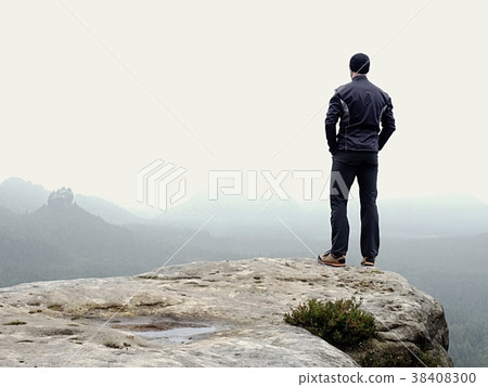Nature hiker on sharp cliff roc watching over mist 38408300
