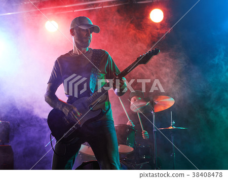 The guitarist performs on stage. 38408478