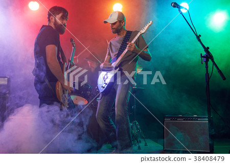 Rock band performs on stage. Guitarist, bass guitar and drums. 38408479