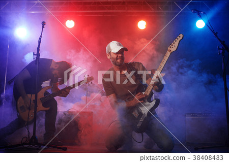 Rock band performs on stage. Guitarist, bass guitar and drums. 38408483