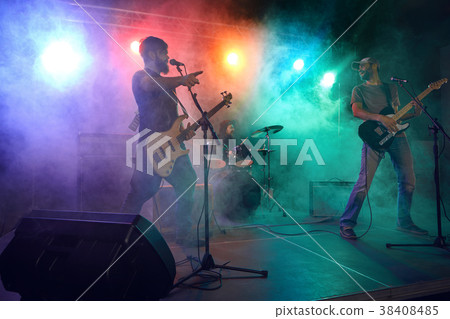 Rock band performs on stage. Guitarist, bass guitar and drums. 38408485