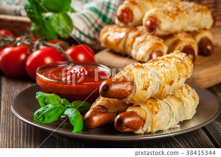 Rolled hot dog sausages baked in puff pastry Rolled hot dog sausages baked in puff pastry 38415344