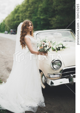 A beautiful bride posing near retro car outdoors A beautiful bride posing near retro car outdoors 38419265