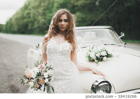 A beautiful bride posing near retro car outdoors 38419266