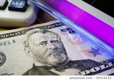Dollar banknotes in a UV light. Counterfeit money. 38419318