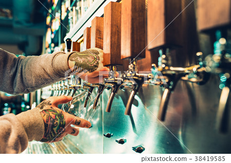 Hand of bartender pouring a large lager beer in Hand of bartender pouring a large lager beer in 38419585