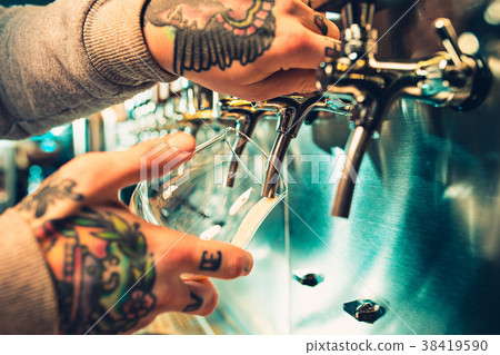 Hand of bartender pouring a large lager beer in Hand of bartender pouring a large lager beer in 38419590