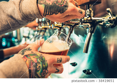 Hand of bartender pouring a large lager beer in 38419651