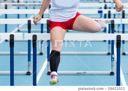 High school girl racing in the hurdles High school girl racing in the hurdles 38422021