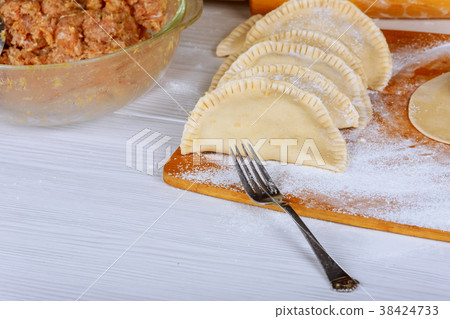 Not roasted cheburek with flour on a wooden board. Not roasted cheburek with flour on a wooden board. 38424733